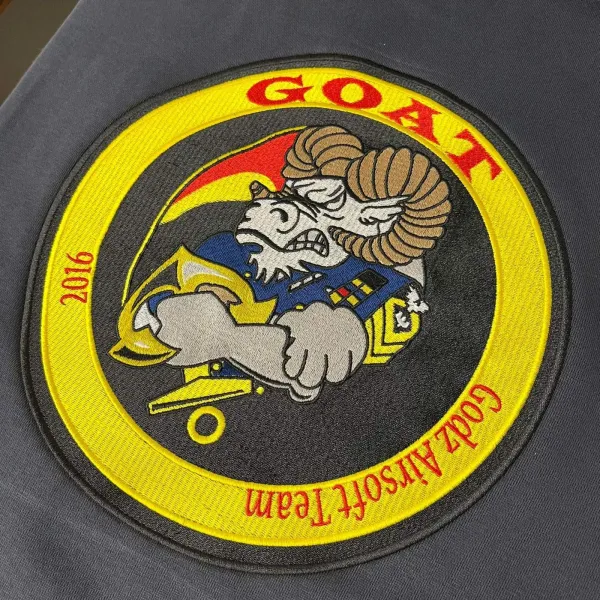 Geborduurd GOAT-embleem van een airsoftteam op grijs textiel